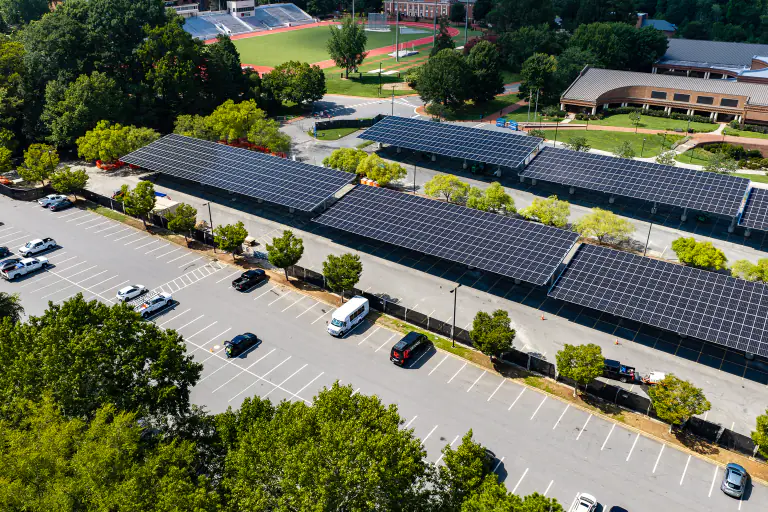 Three rows of solar carport canopies beside campus academic buildings