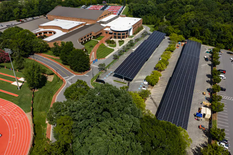 Solar carport canopies with a brick campus building and running track behind