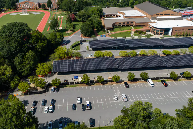 Aerial of a solar canopy run beside a campus athletic field