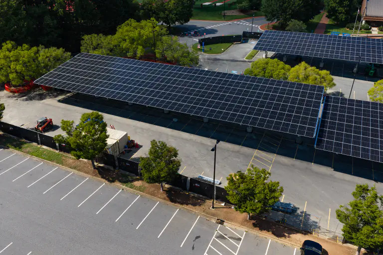 Low aerial close-up of a solar carport canopy showing the module layout