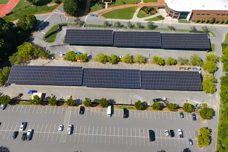 Long rows of solar canopies stretching across a campus parking lot