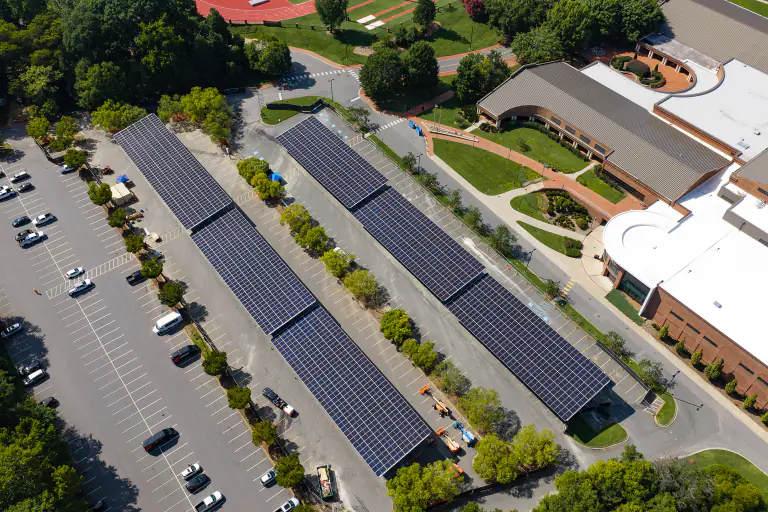 Diagonal aerial of solar canopy rows beside a curved campus building