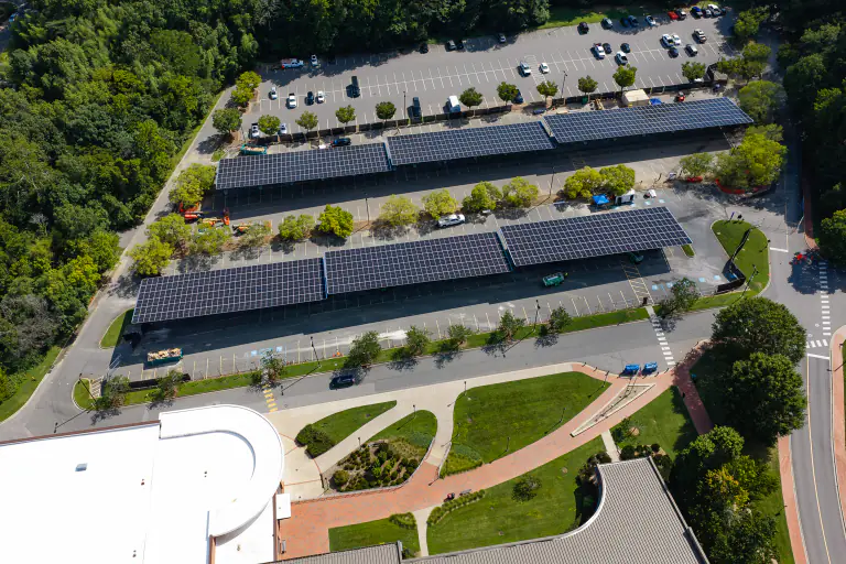 Solar carport canopies next to a white-roofed campus building