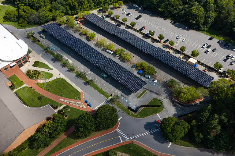 Solar canopies over parking with a brick campus building alongside