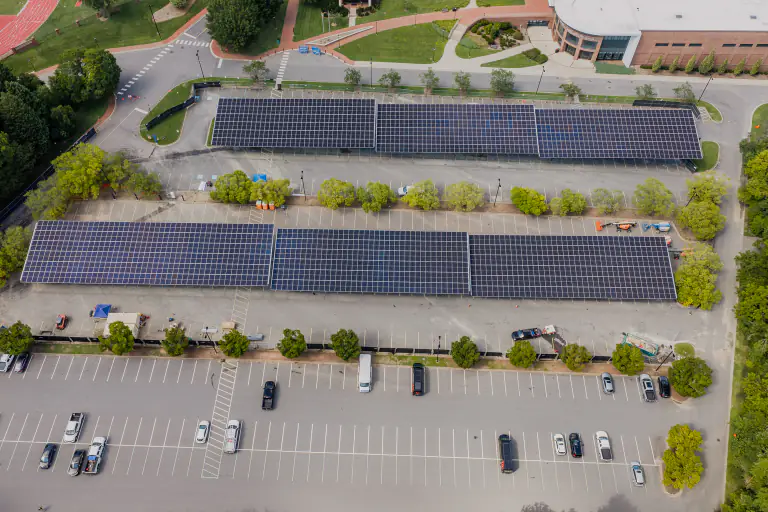 Two solar canopy runs over a parking lot with cars parked underneath