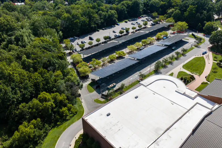 Solar canopy rows beside a white-roofed campus building