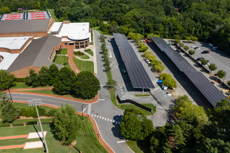 Two solar carport canopy rows with a campus athletic field behind