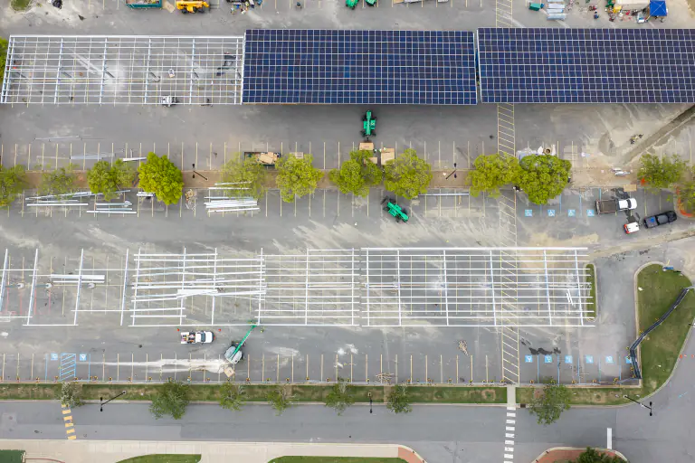 Top-down aerial showing completed solar panels beside empty canopy framework