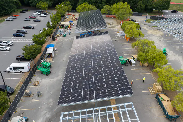 Solar modules being installed on a canopy with crew and equipment below