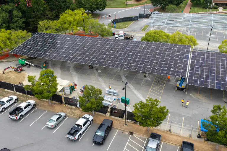 Solar carport canopy nearing completion with crew working underneath